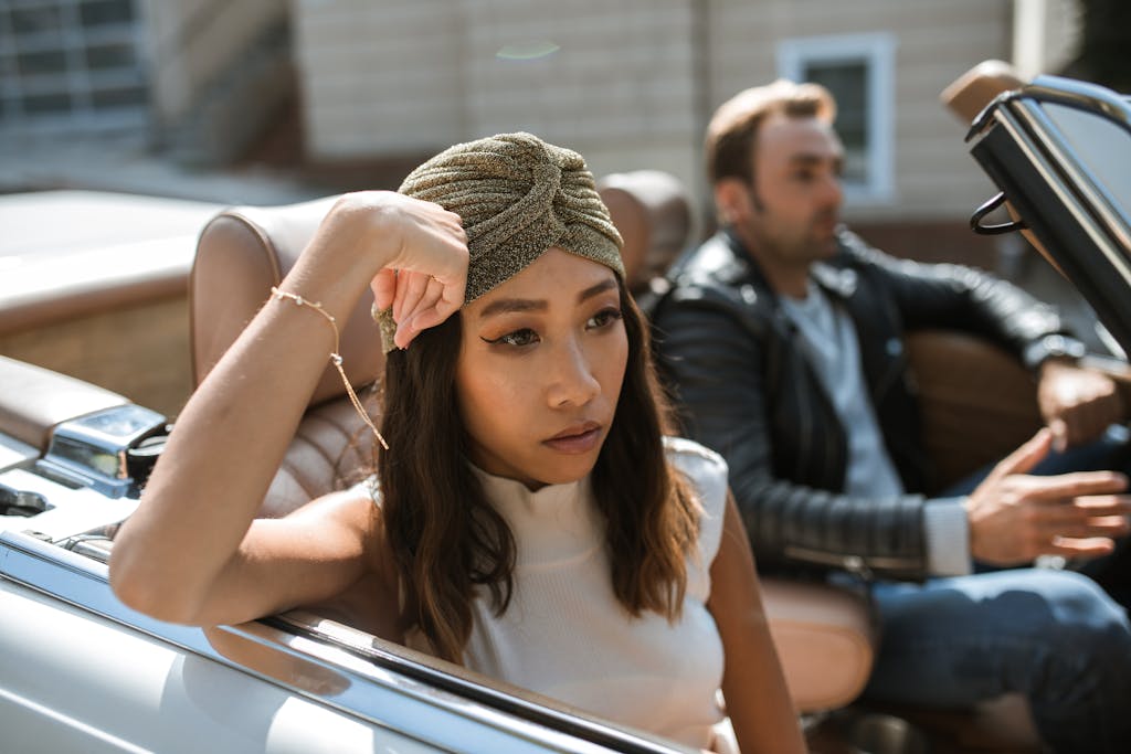 A couple having an intense discussion while seated in a convertible car.
