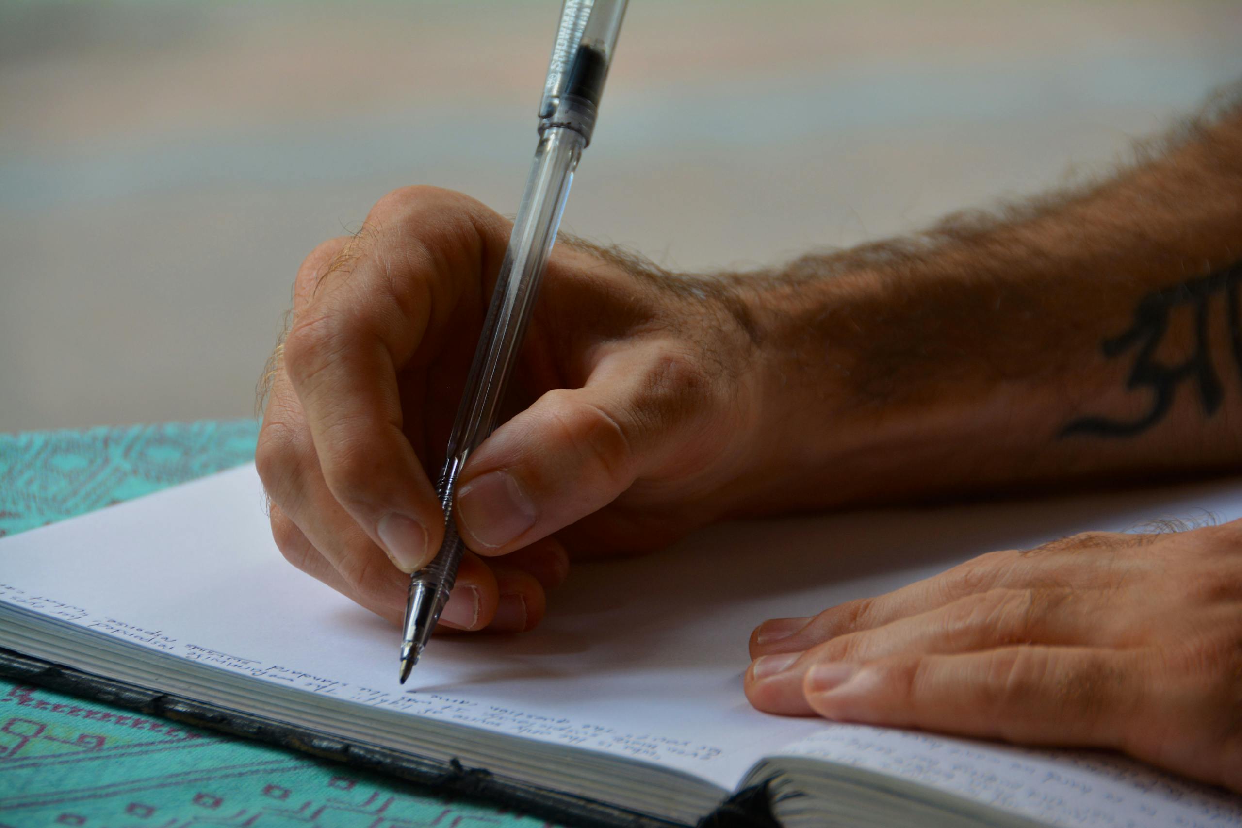 Close-up of a person writing in a notebook, focusing on hands and pen, ideal for study or business themes.